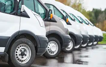 Row of commercial vans parked in a lot, showcasing the vehicles relevant to cannabis commercial auto insurance services.